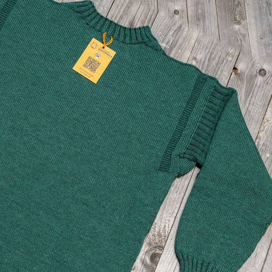Traditional Salty Sea green wool guernsey sweater with ribbed shoulder detailing and a size 36 tag on a wooden background.