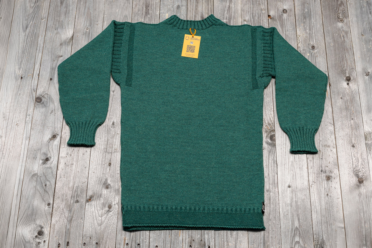Traditional Salty Sea green wool guernsey sweater with ribbed cuffs and shoulder detailing on a wooden background.