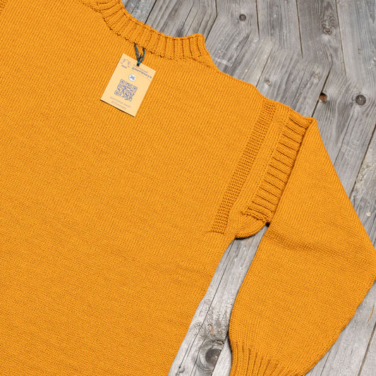 Golden yellow pure wool traditional guernsey sweater with ribbed shoulder detail and size 36 tag on wooden background.
