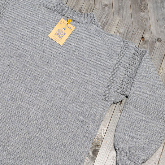 Granite grey traditional wool guernsey sweater with ribbed detailing and a size 36 tag on a rustic wooden background.